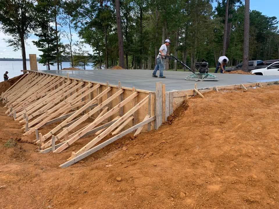 A man is standing in the dirt next to a wooden structure.