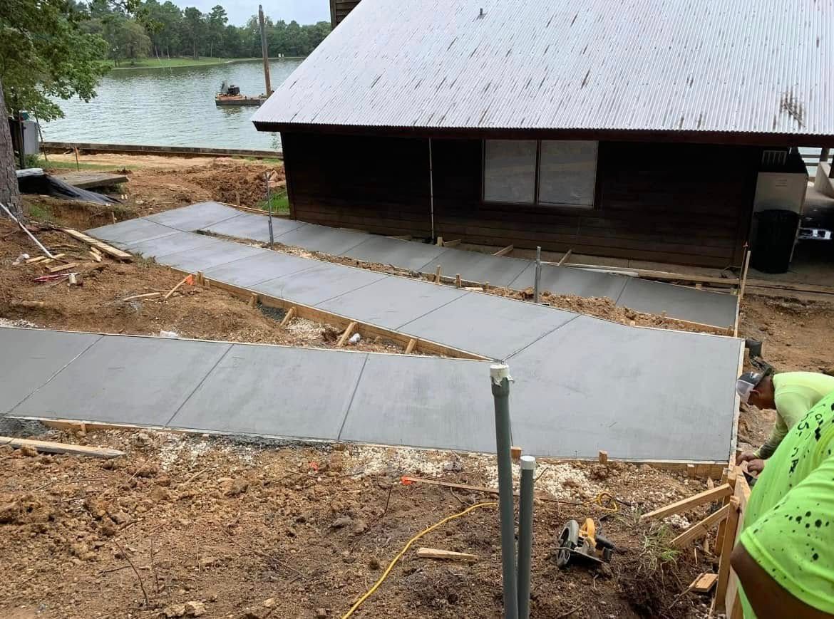 A man is working on a concrete walkway in front of a house.
