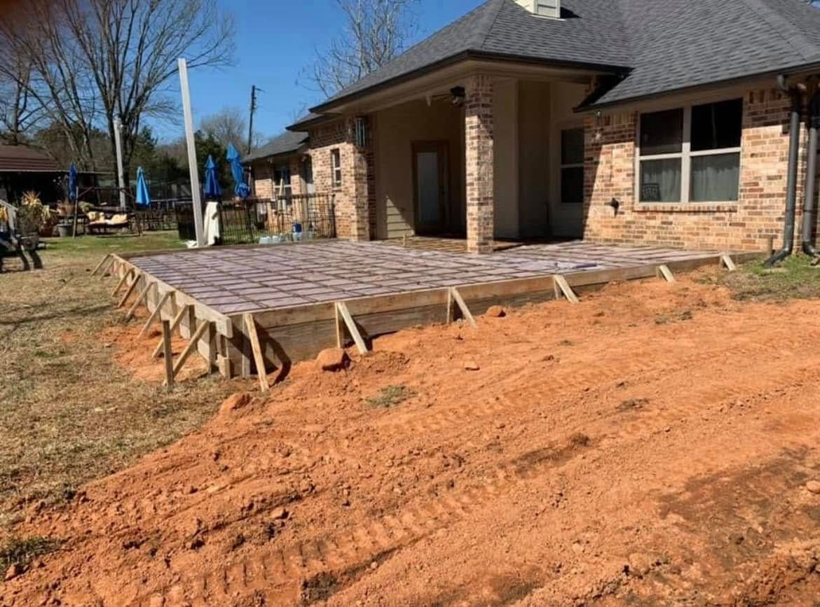A brick house with a concrete deck being built in front of it.