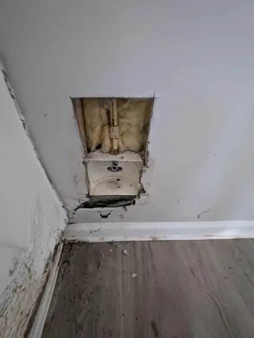 A hole in the ceiling of a room with a wooden floor.
