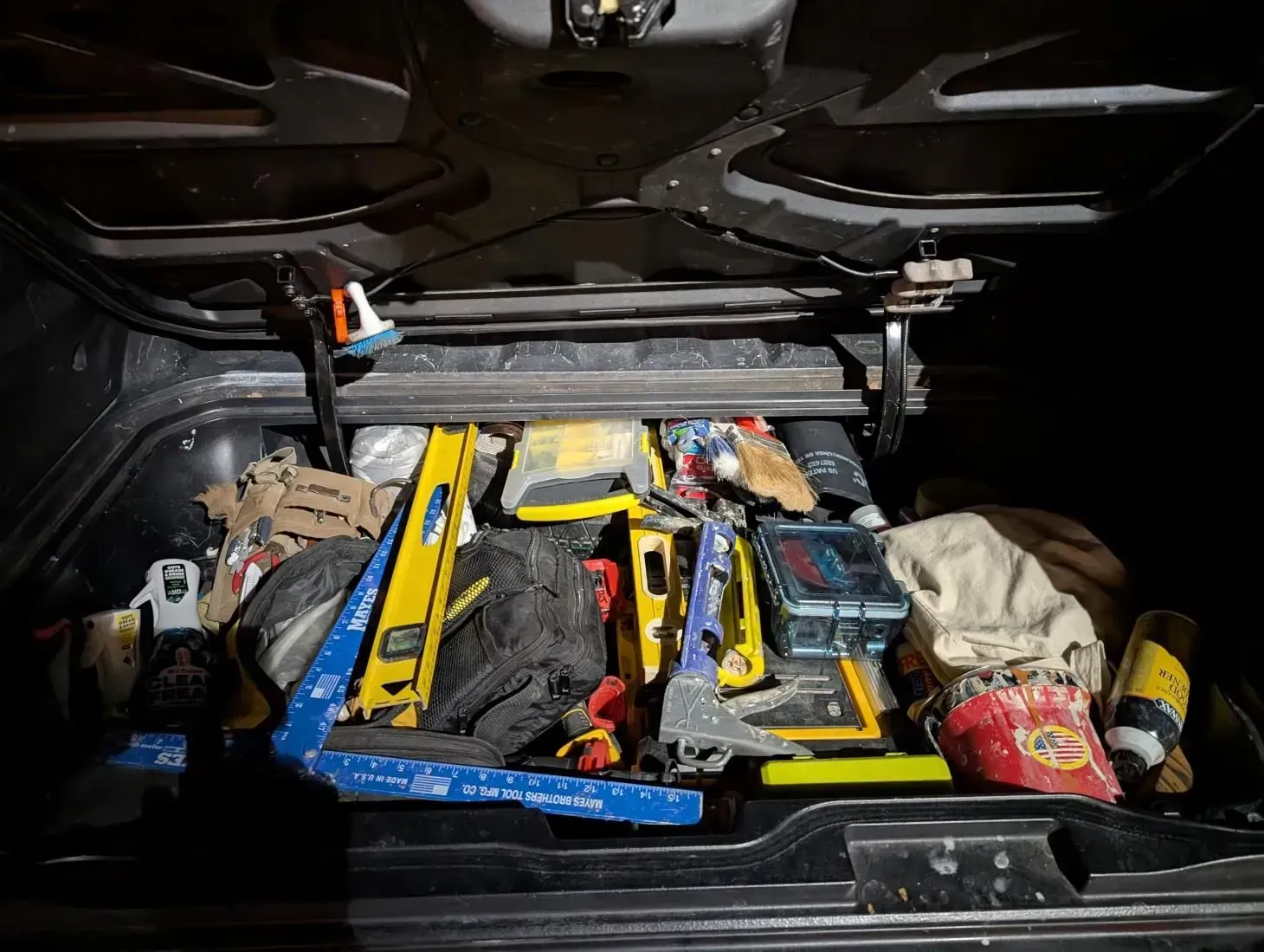 The trunk of a car is filled with lots of tools.