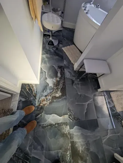 A person is standing on a tiled floor in a bathroom.