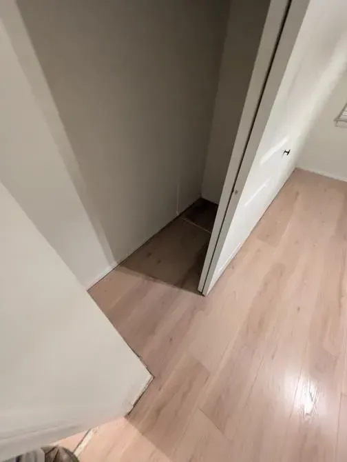 A person is standing in a hallway with a wooden floor.