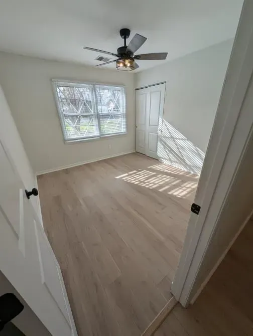 A bedroom with hardwood floors and a ceiling fan.