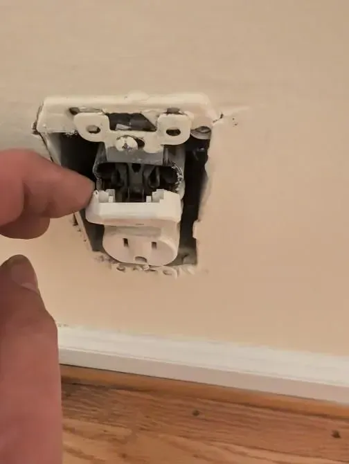 A person is plugging an electrical outlet into a wall.