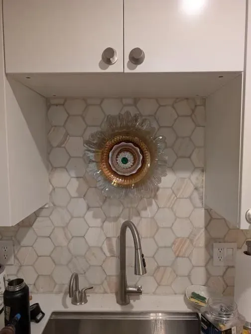 A kitchen sink with a stainless steel faucet and a painting on the wall above it.