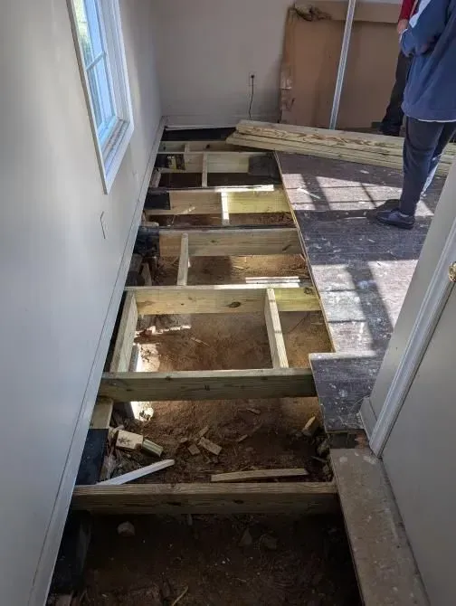 A person is standing on a wooden floor in a room.