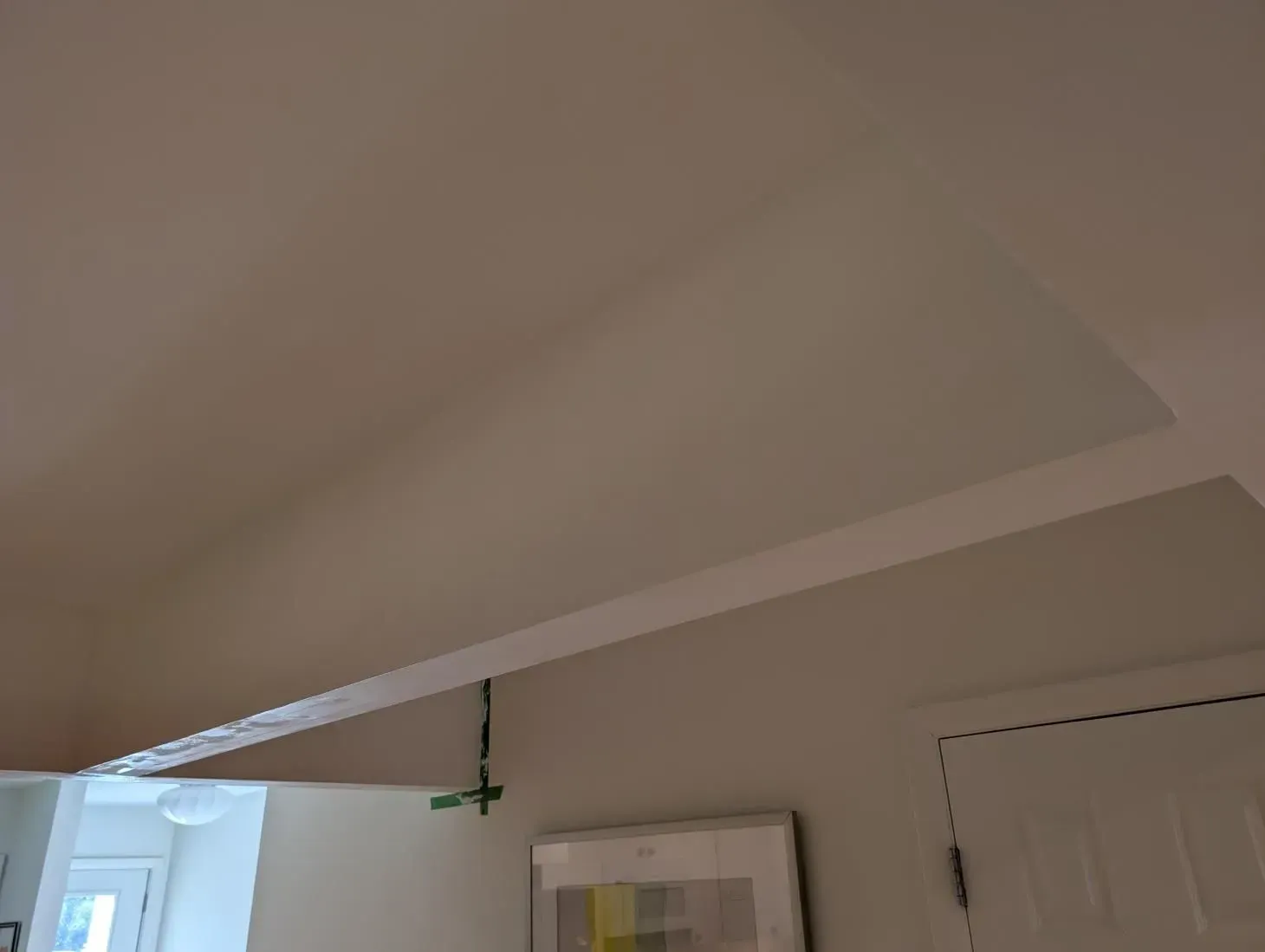 A picture is hanging on a wall next to a door in a room.