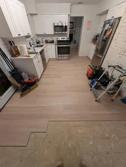 A kitchen with a wooden floor and white cabinets.