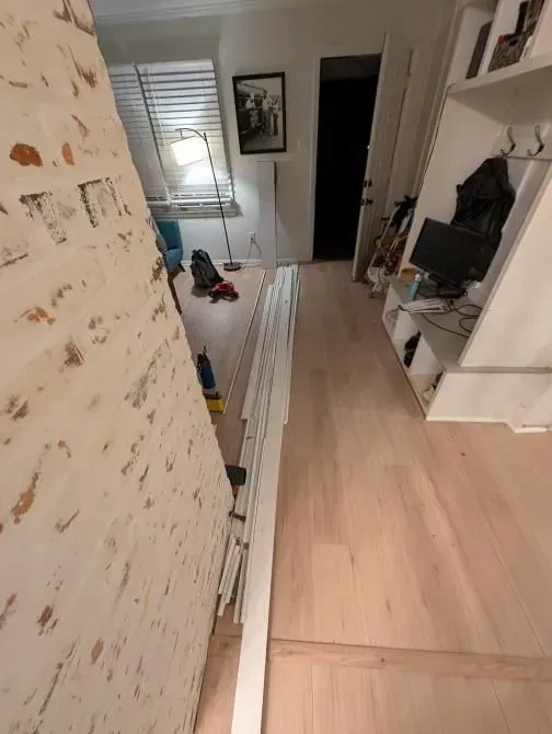 A hallway with a wooden floor and a white railing.