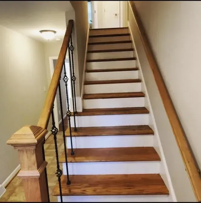 A wooden staircase with white steps and a metal railing