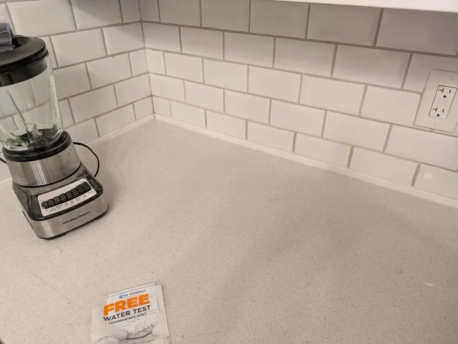 A blender is sitting on a counter next to a free water test.