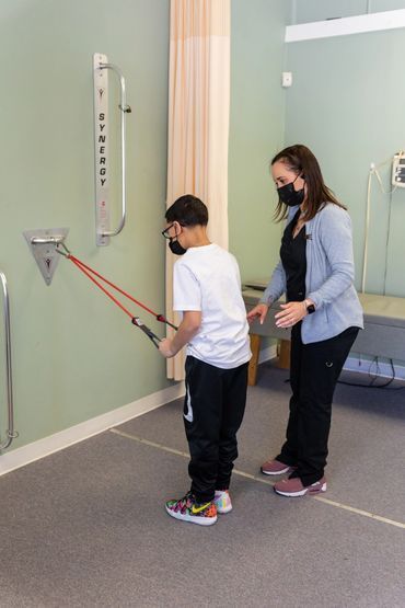 Person using resistance bands with a therapist in a physical therapy room.
