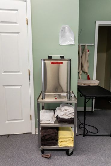 Stainless steel towel warmer on a rolling cart with stacked towels.