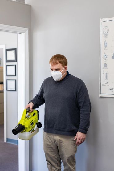 Man in a mask sanitizing a room with a fogger.
