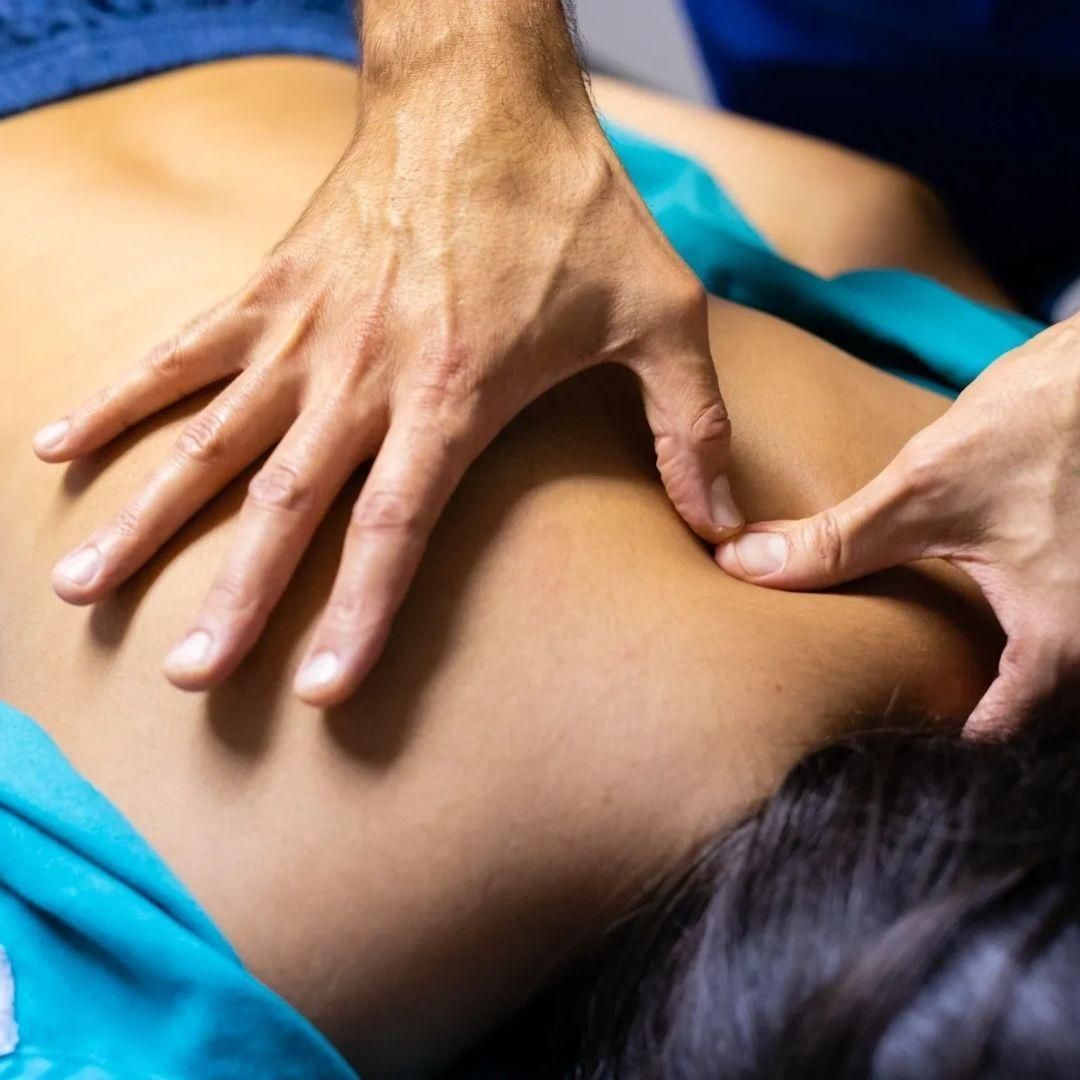 Person receiving back massage, hands applying pressure on the shoulder and back.