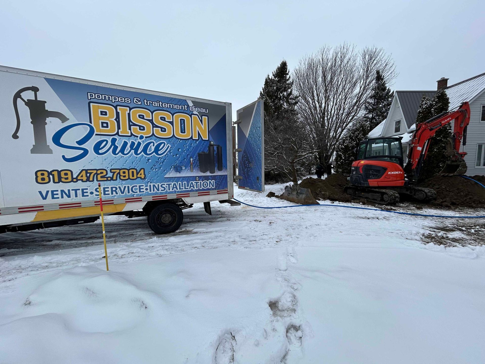 Un camion de service Bisson est stationné dans la neige devant une maison.