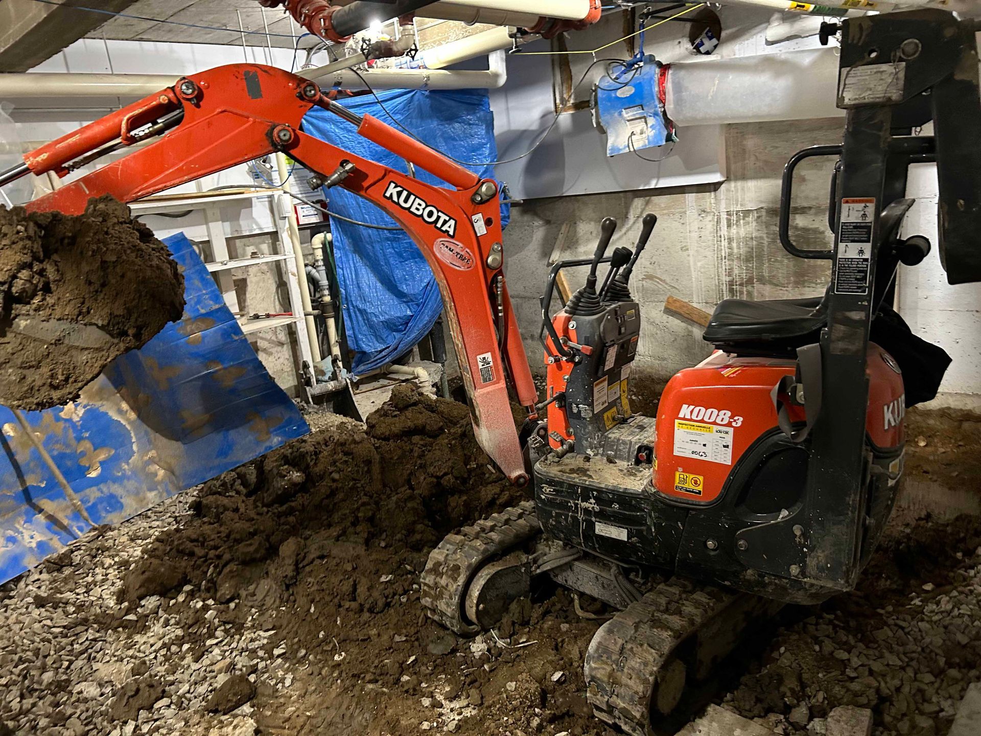 Une petite excavatrice creuse un trou dans un sous-sol.