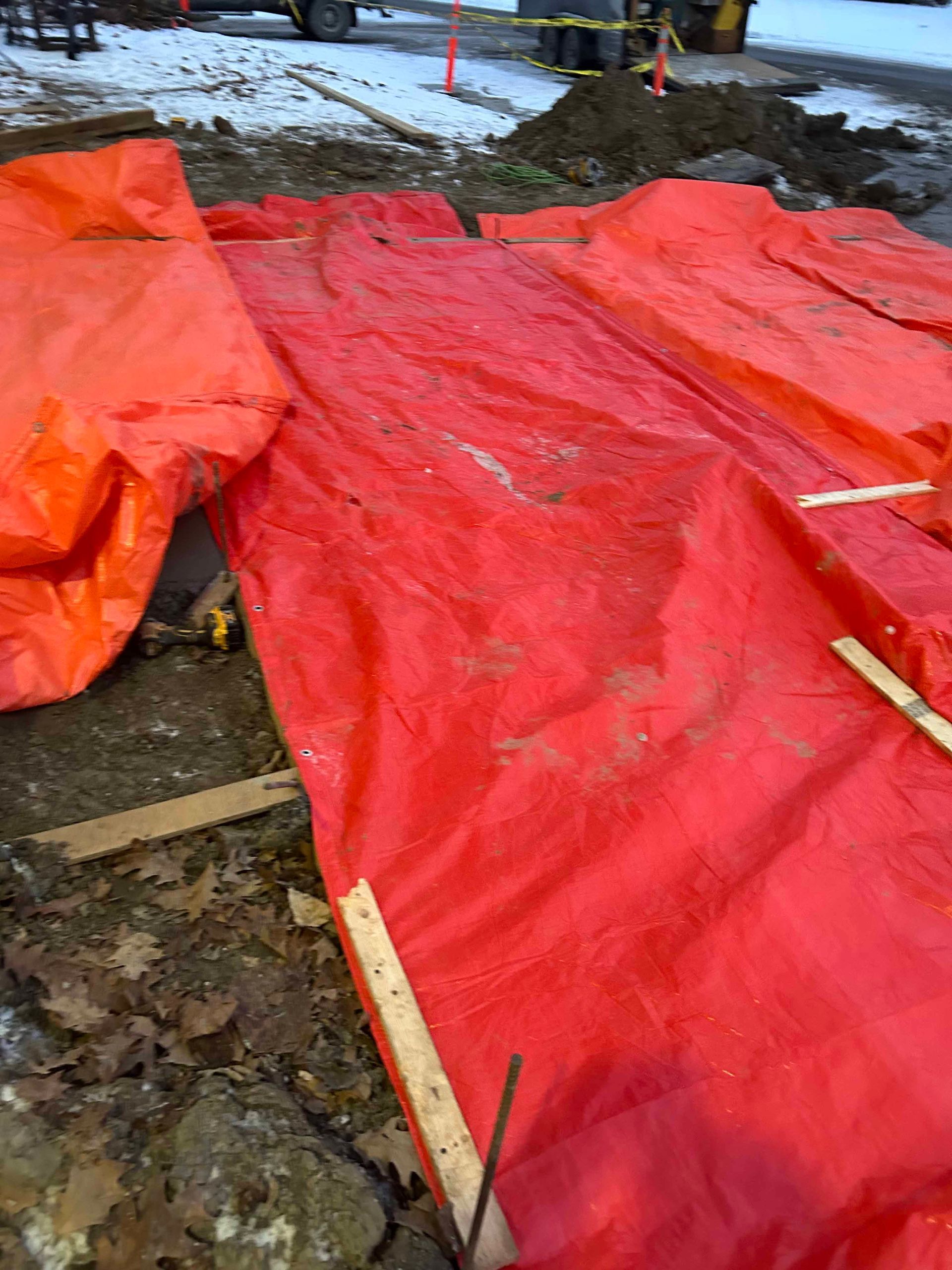 Une grande bâche rouge est posée sur le sol d'un chantier de construction.