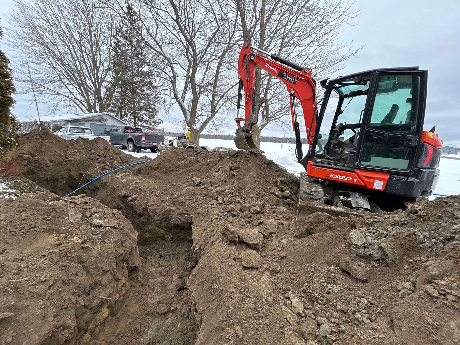 Une excavatrice rouge et noire creuse un trou dans la terre.