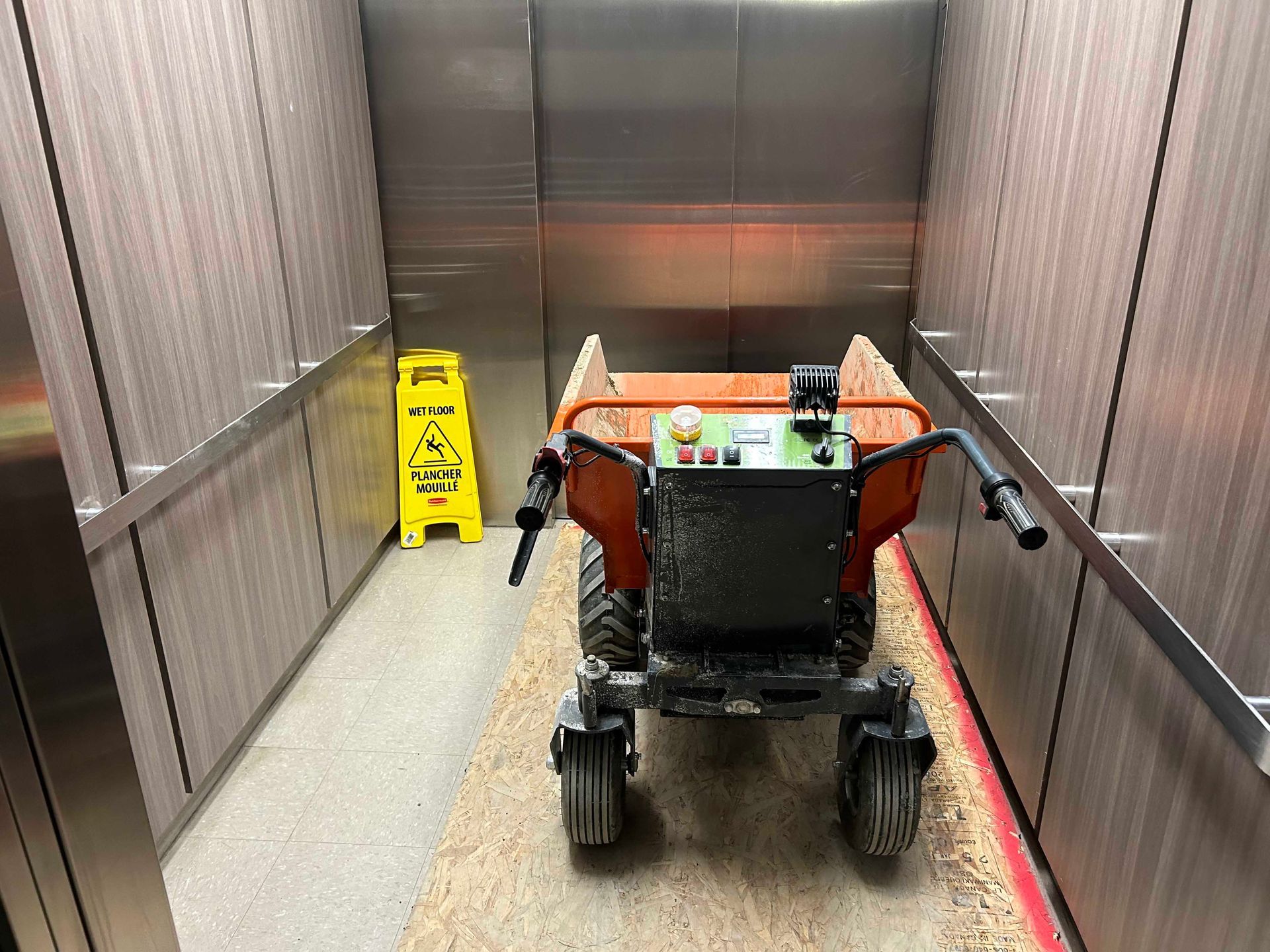 Un camion à benne basculante est assis dans un ascenseur à côté d'un panneau d'avertissement jaune.