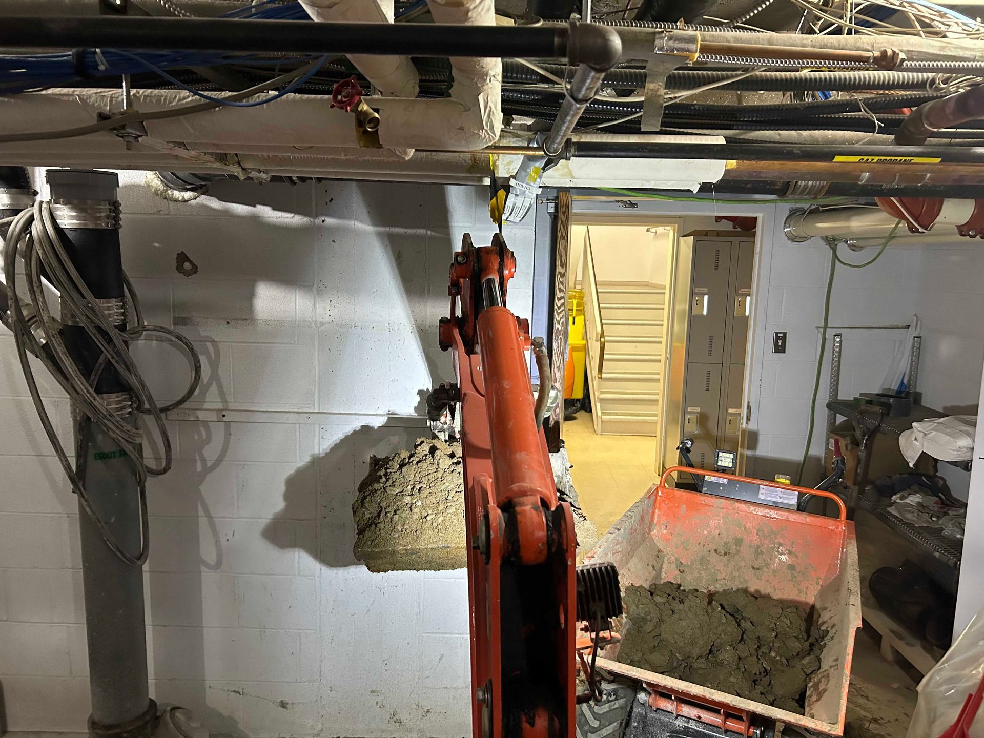 Une grue soulève un gros rocher dans un sous-sol.