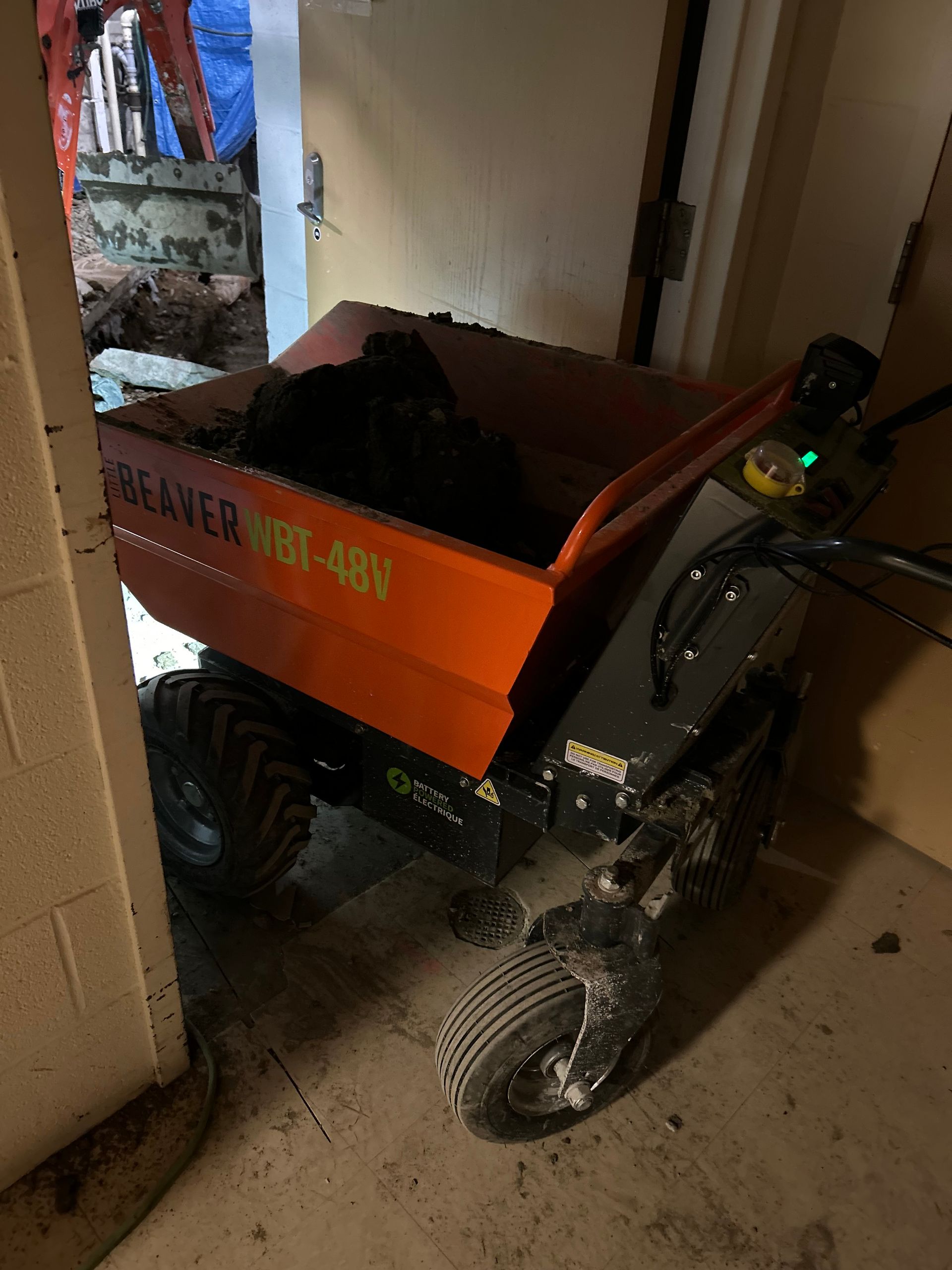 Un camion-benne orange est garé dans un garage à côté d'une porte.