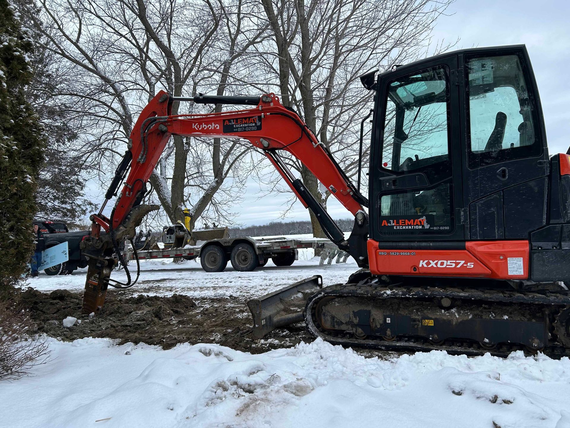Une excavatrice rouge et noire est garée dans la neige.