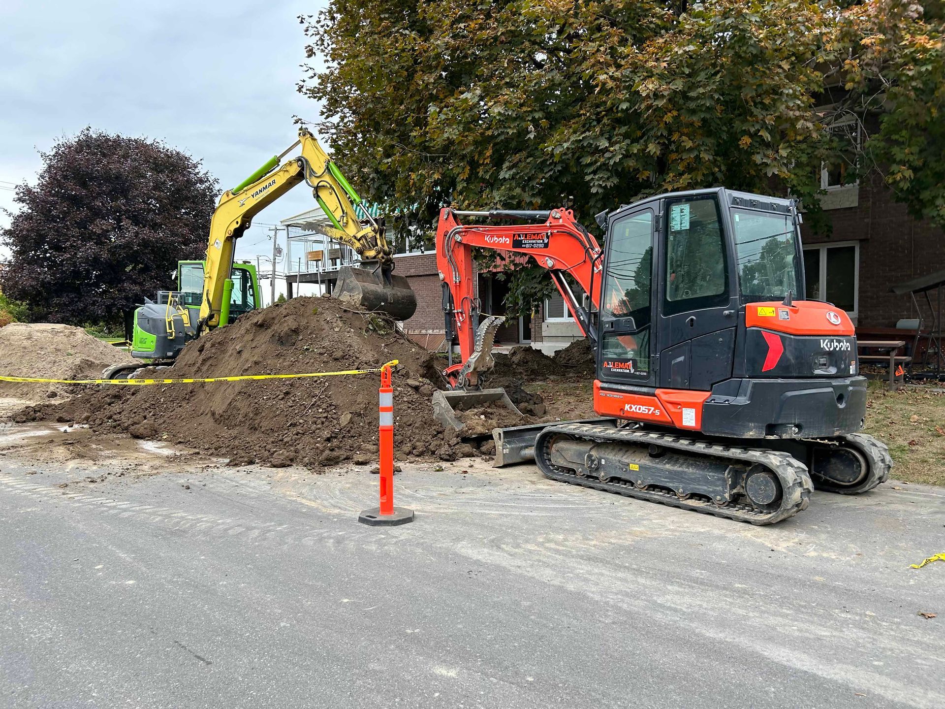 Deux excavatrices travaillent sur un chantier de construction à côté d'un tas de terre.