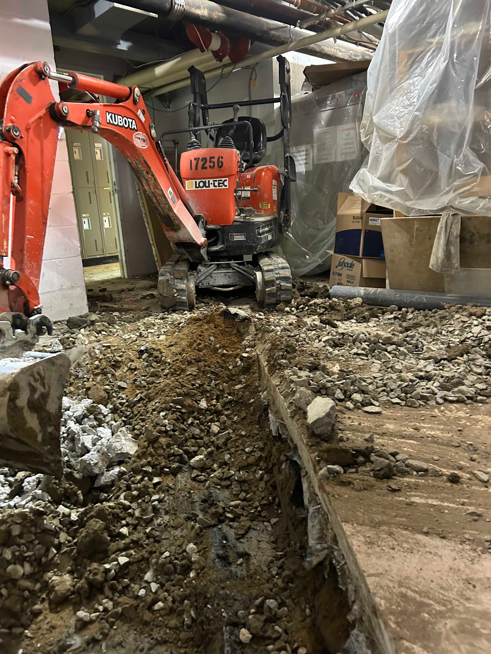 Une petite excavatrice orange creuse un trou dans le sol.