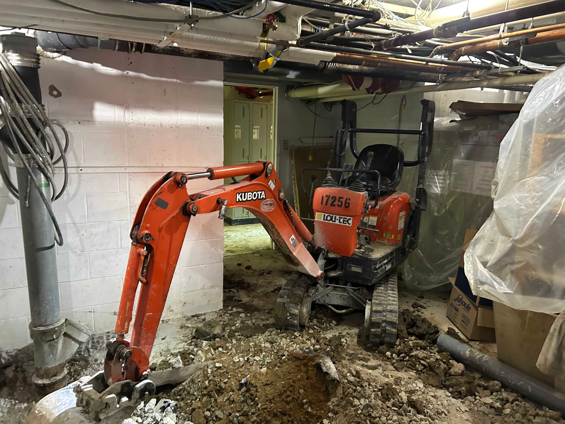 Une petite excavatrice creuse un trou dans un sous-sol.