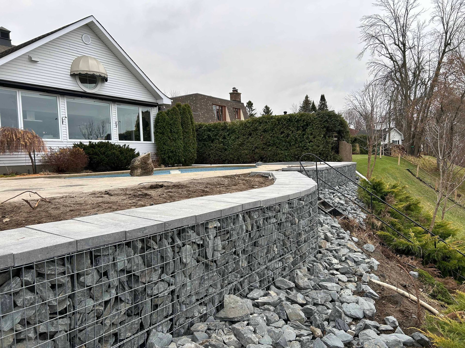 Un mur de pierre est en train d'être construit devant une maison.