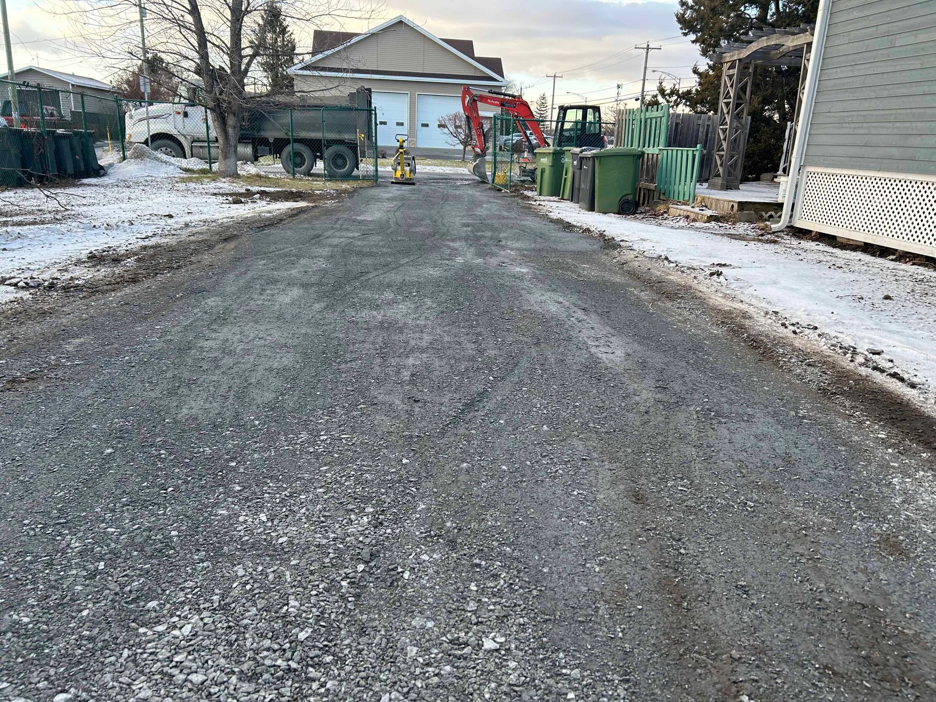 Une rue enneigée avec un camion à benne basculante garé sur le côté.