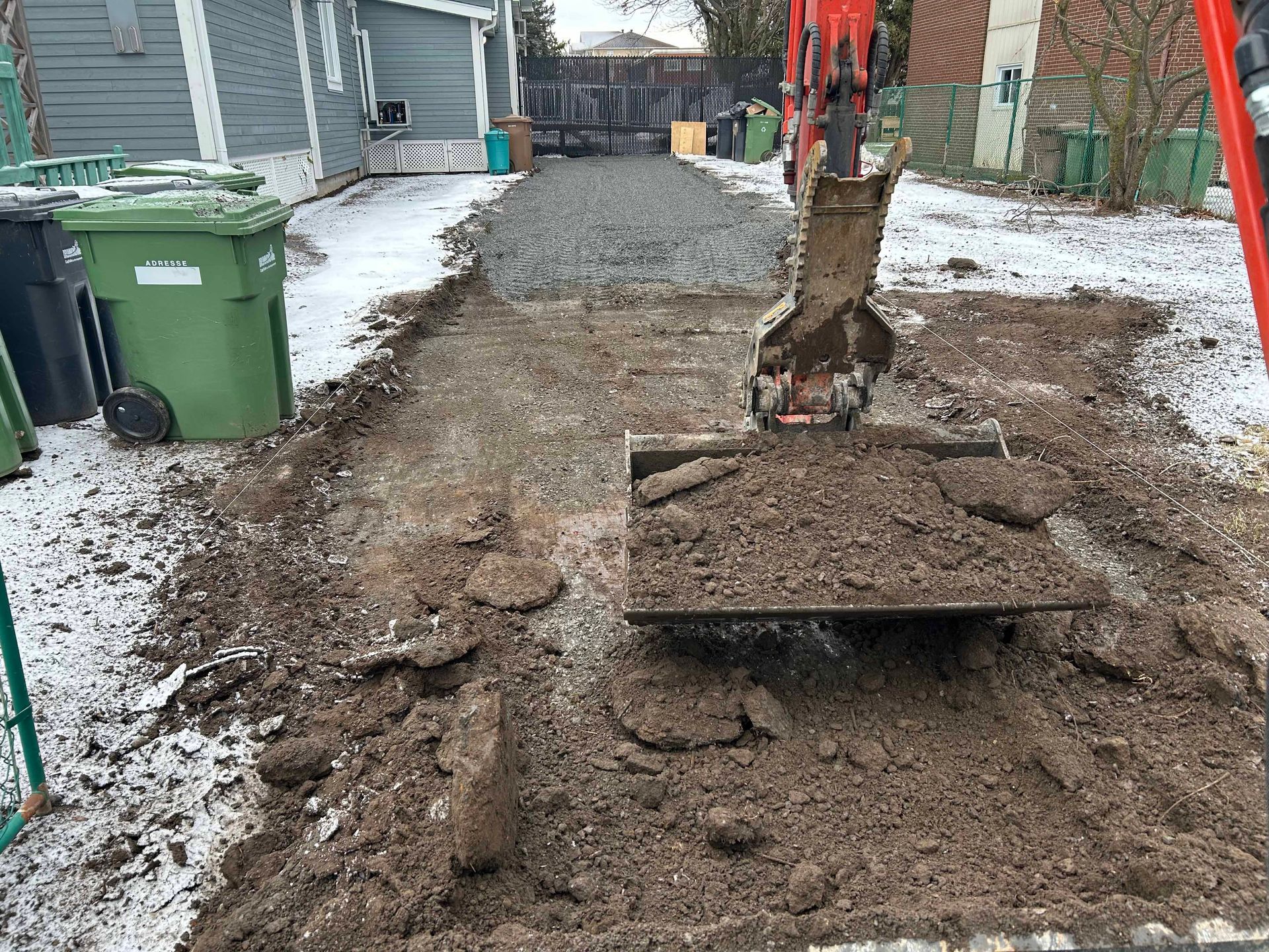 Une excavatrice creuse un trou dans la terre d'une allée.