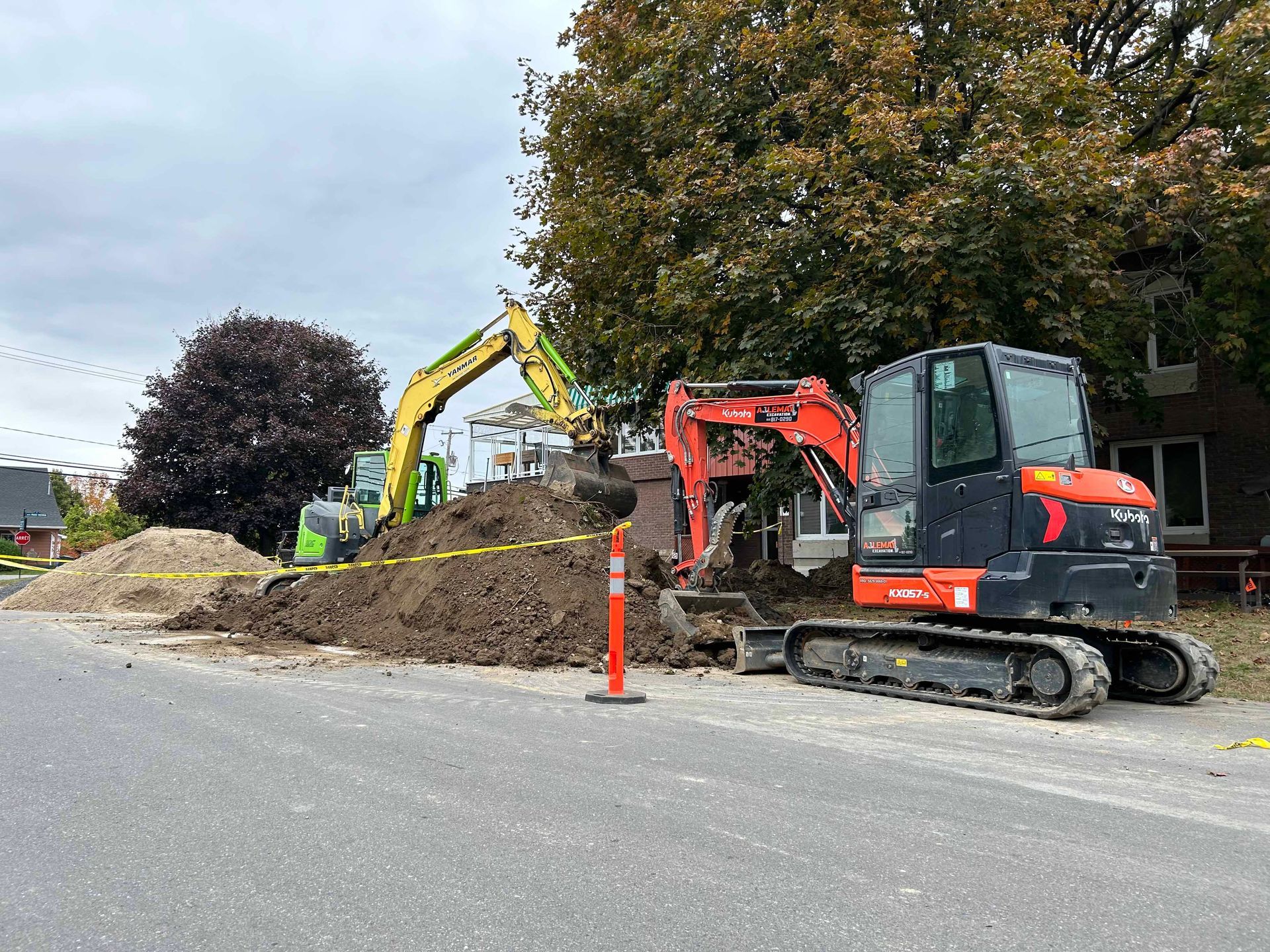 Une excavatrice creuse un trou dans le sol à côté d'un tas de terre.