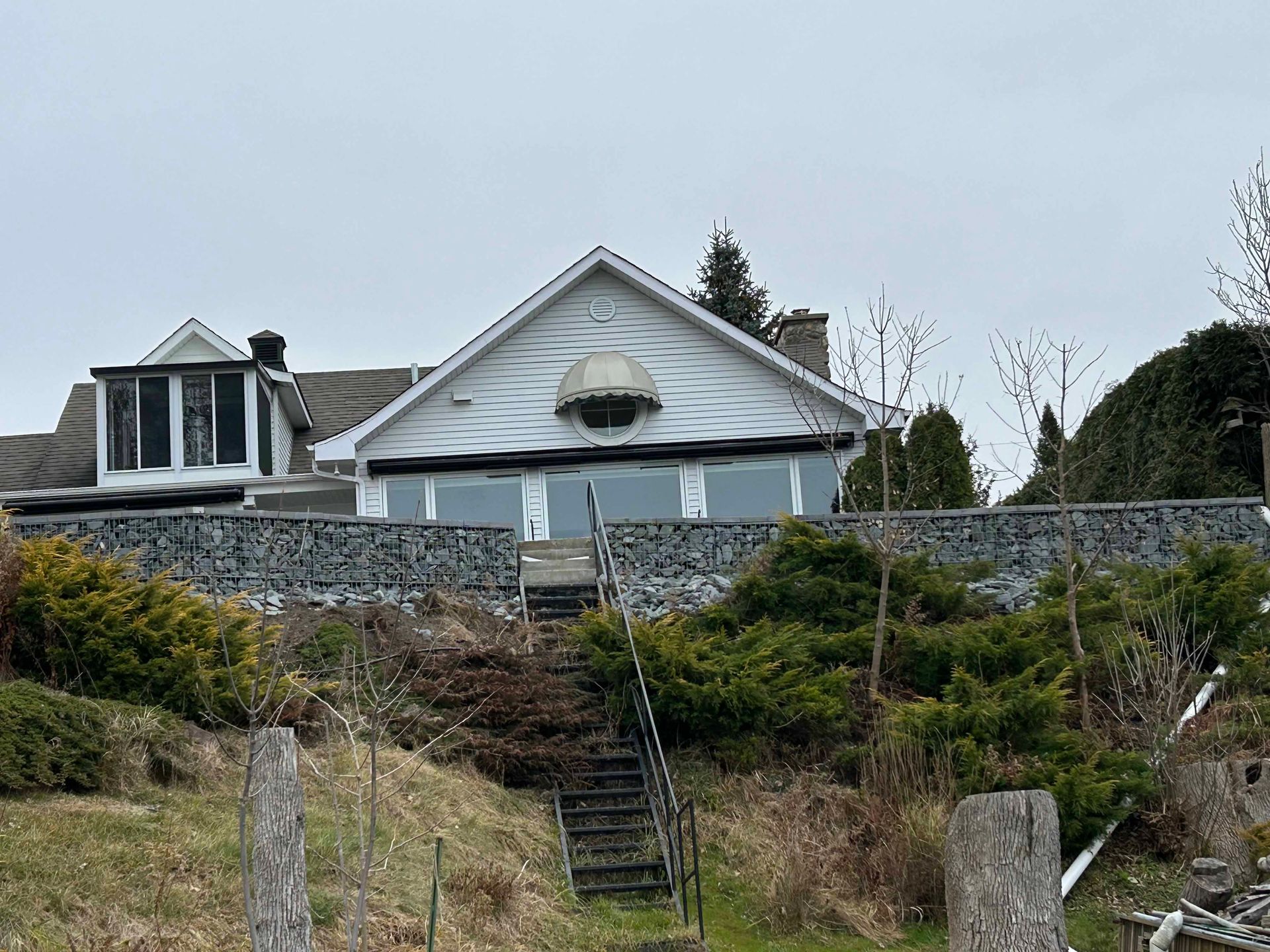 Une grande maison blanche est assise au sommet d'une colline à côté d'un mur de pierre.
