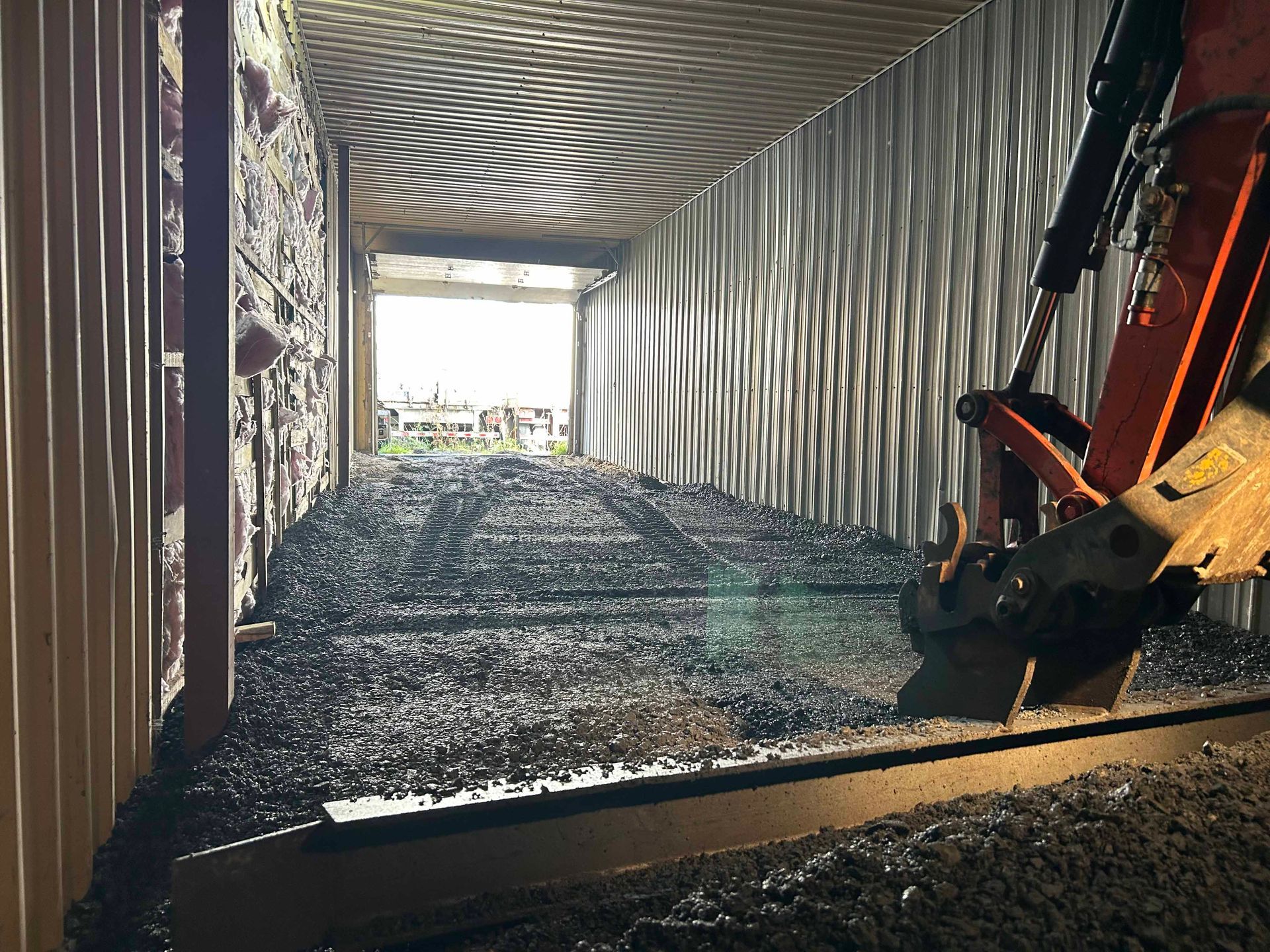 Une petite excavatrice creuse un tunnel dans un bâtiment.