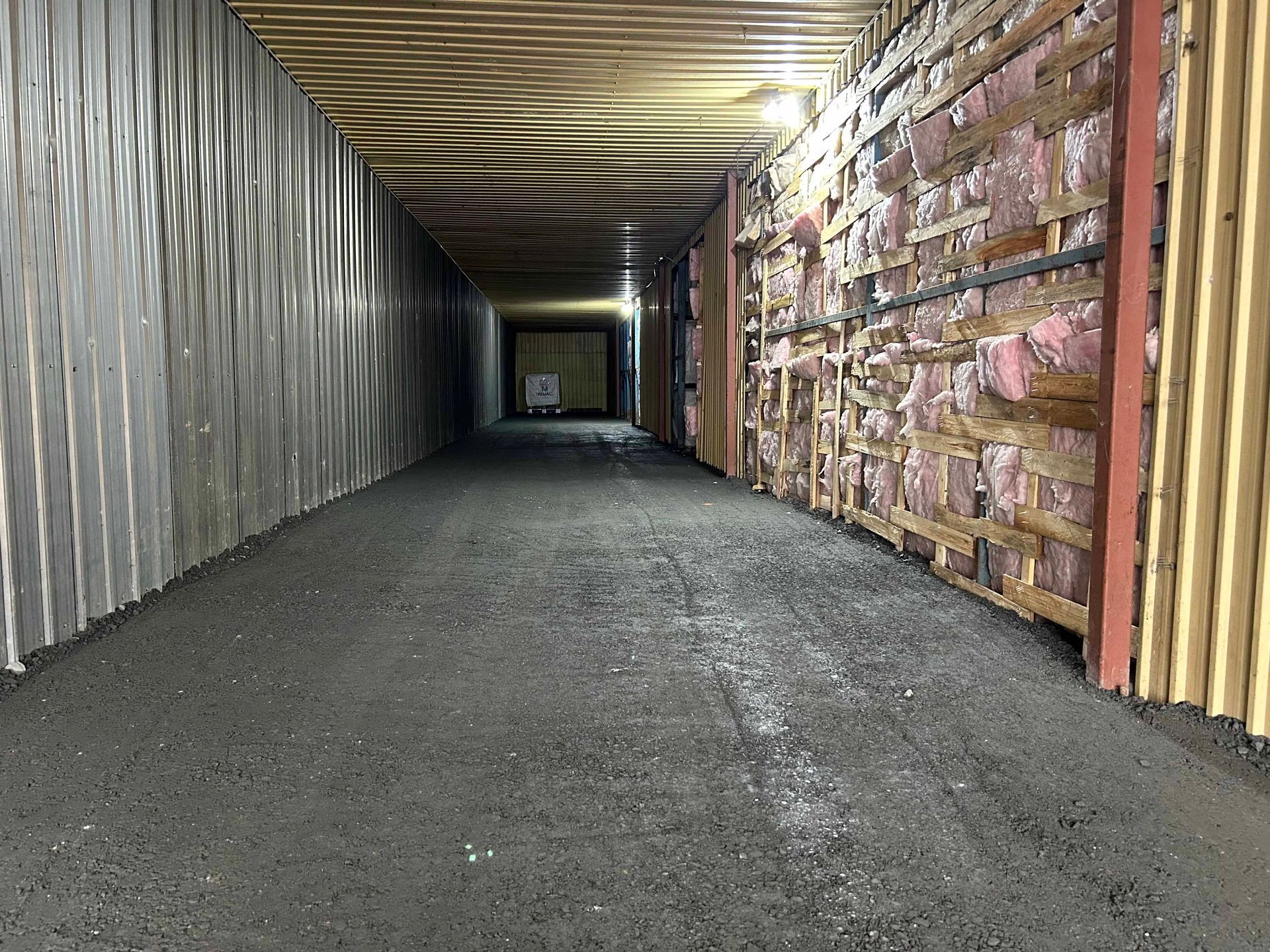 Un long tunnel avec beaucoup de murs en bois et un sol en béton.