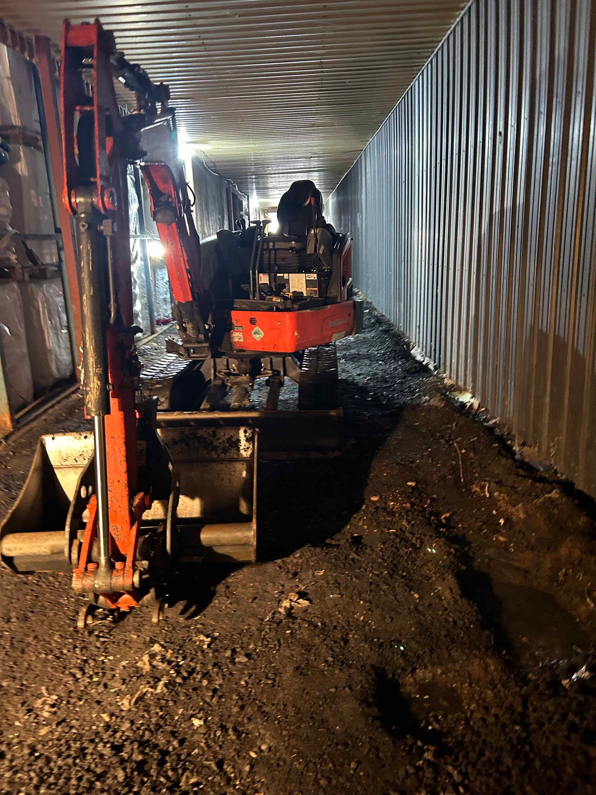 Une excavatrice déplace de la terre dans un tunnel la nuit.