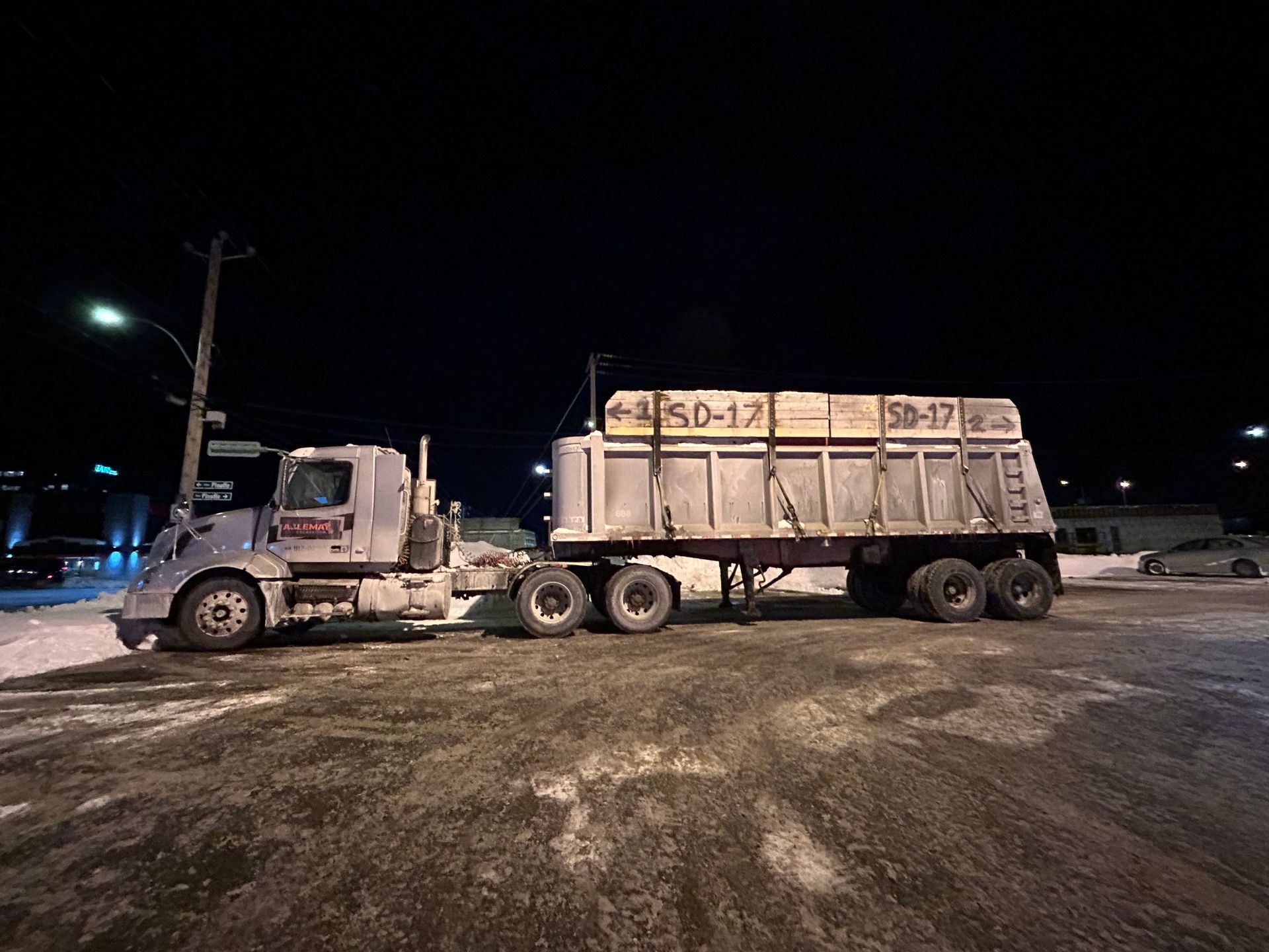 Un camion à benne basculante est garé sur un parking la nuit.