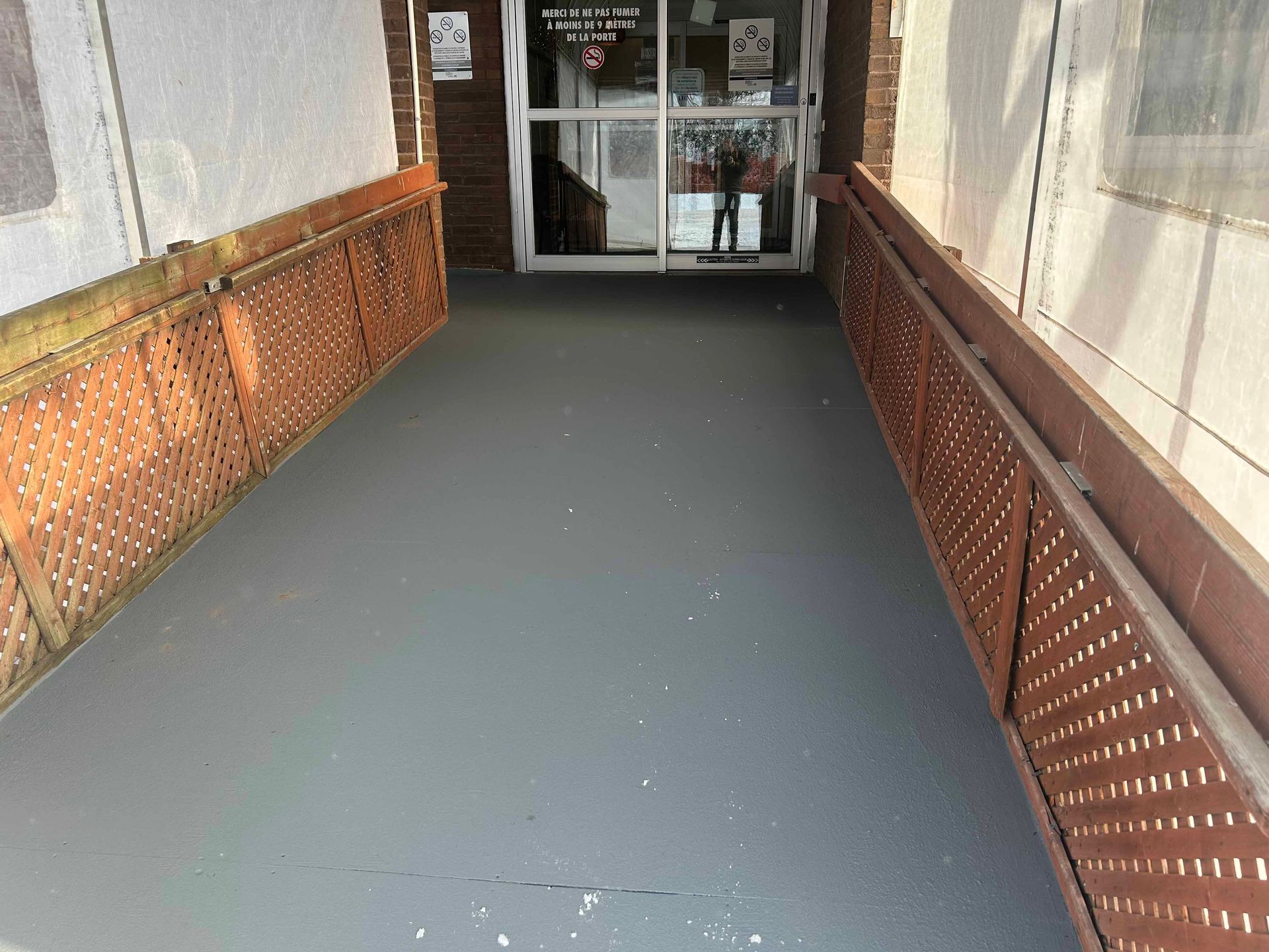 Une passerelle menant à un bâtiment avec une porte coulissante en verre.