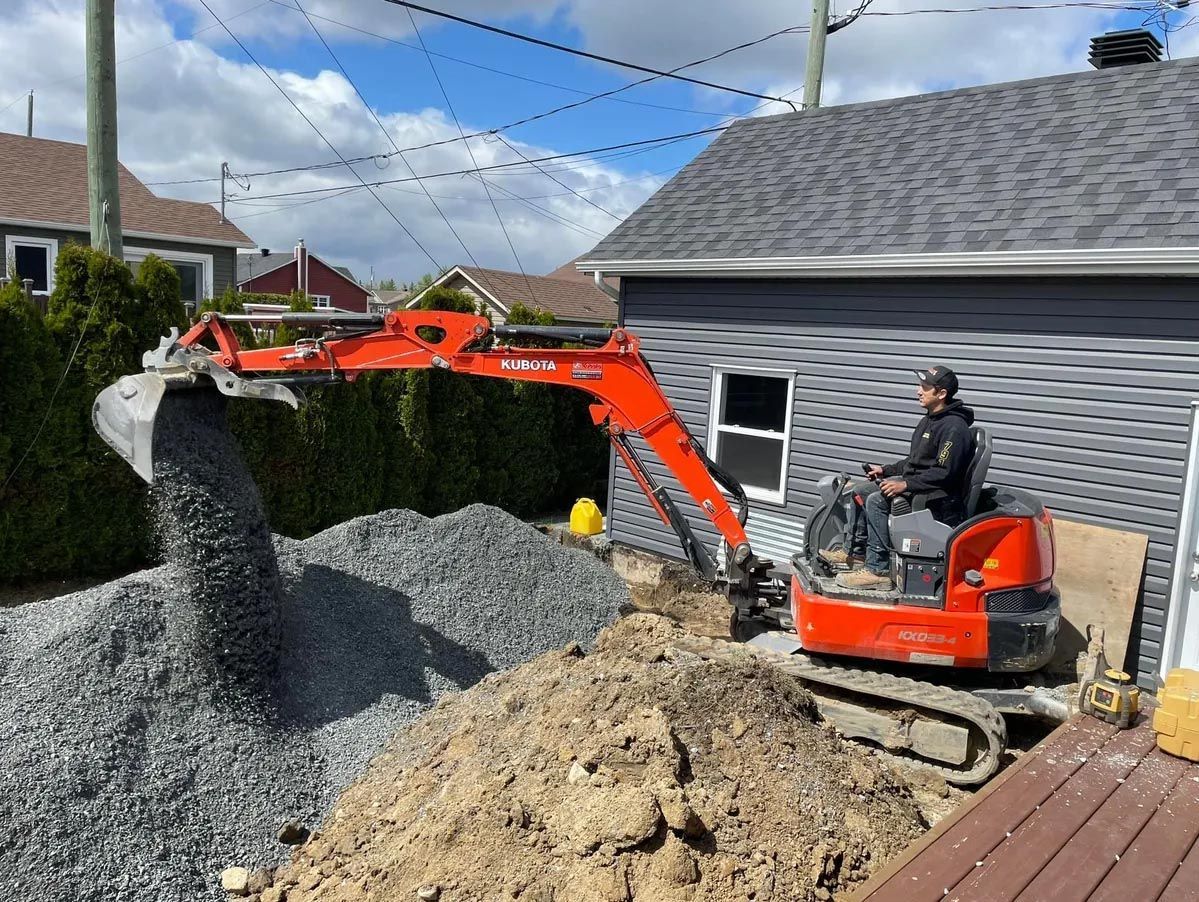 Un homme conduit une petite excavatrice devant une maison.