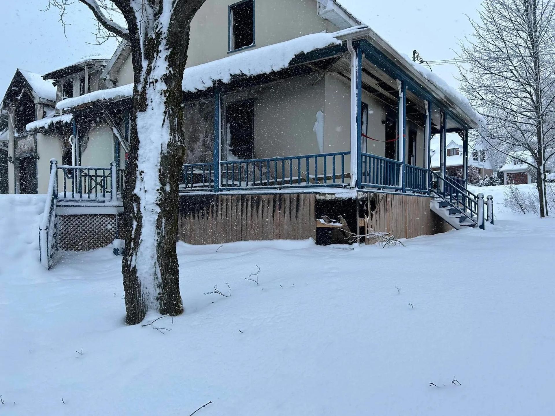 Une maison avec un porche et des escaliers est recouverte de neige.