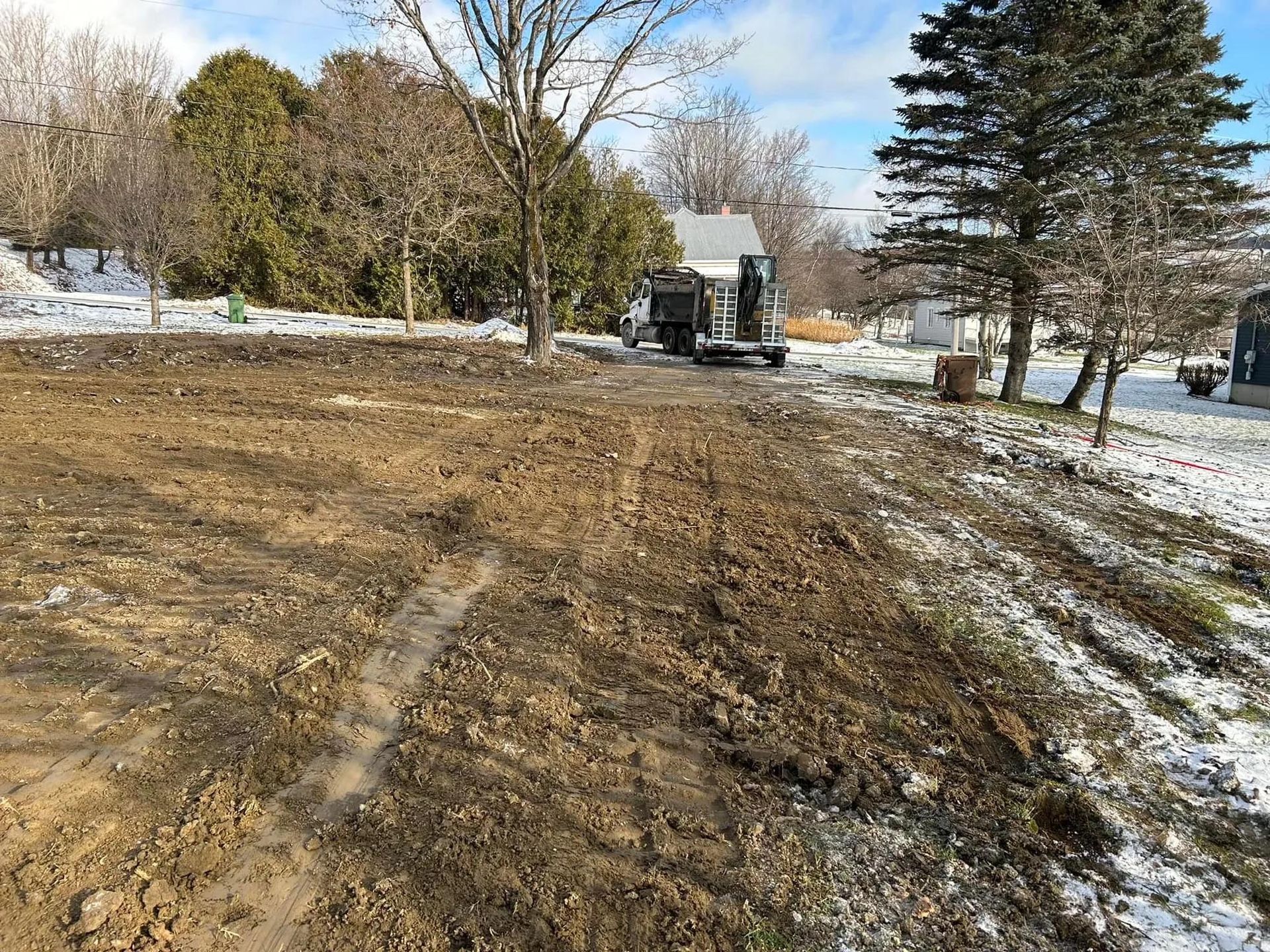 Un camion roule sur un chemin de terre à côté d'un champ enneigé.