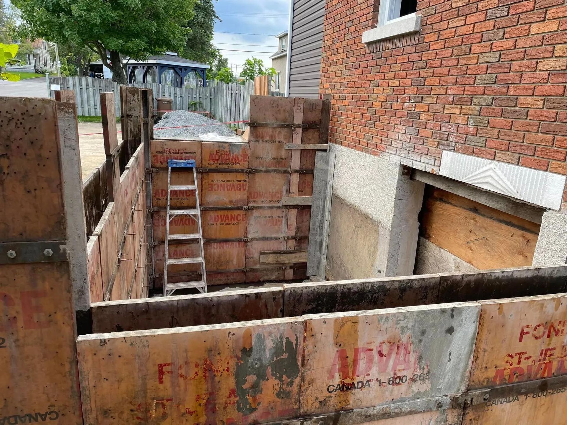 Une échelle est posée devant un bâtiment en briques en construction.