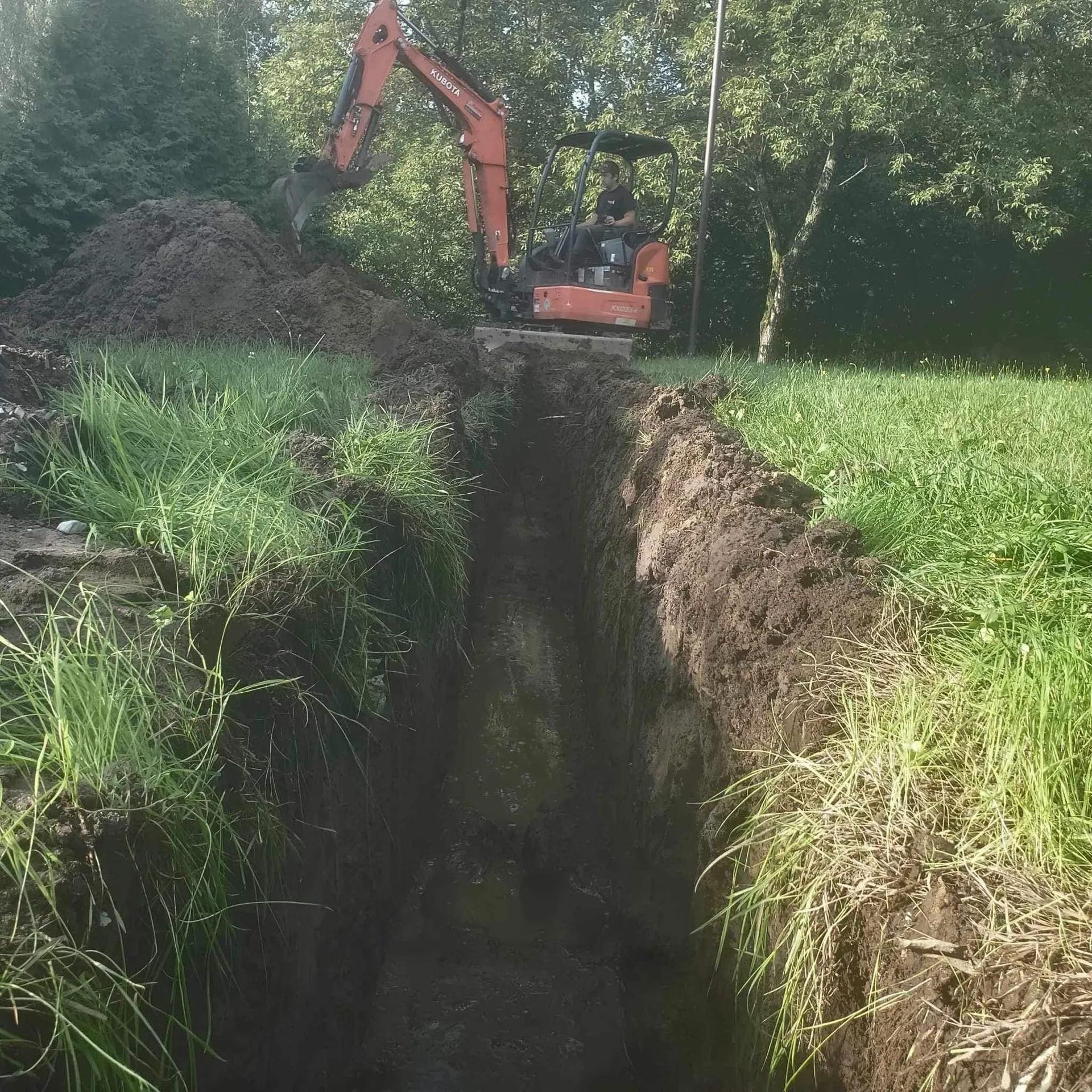 Une excavatrice creuse un trou dans un champ herbeux