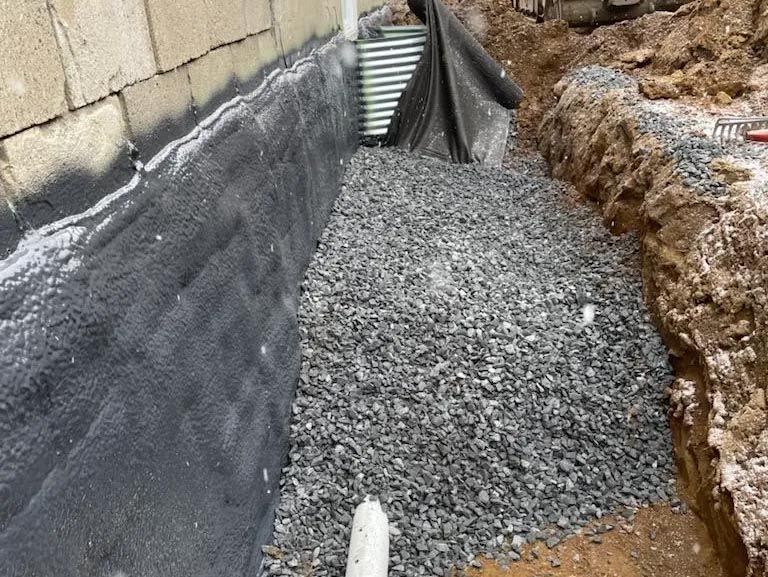 Un tas de gravier est posé devant un mur de briques.