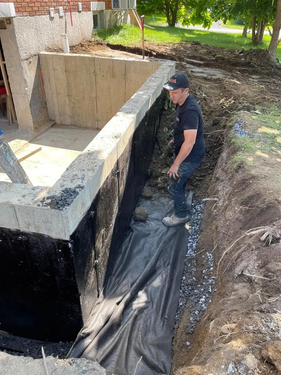 Un homme se tient dans une tranchée à côté d'un mur en béton.