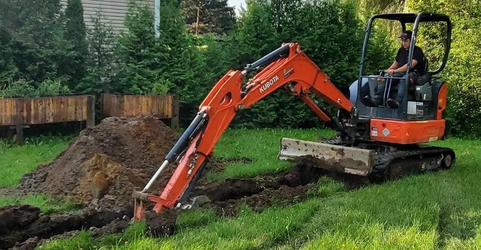Un homme conduit une petite excavatrice orange dans un champ herbeux.
