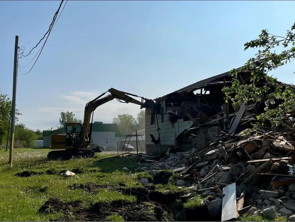 Une excavatrice démolit un bâtiment dans un champ